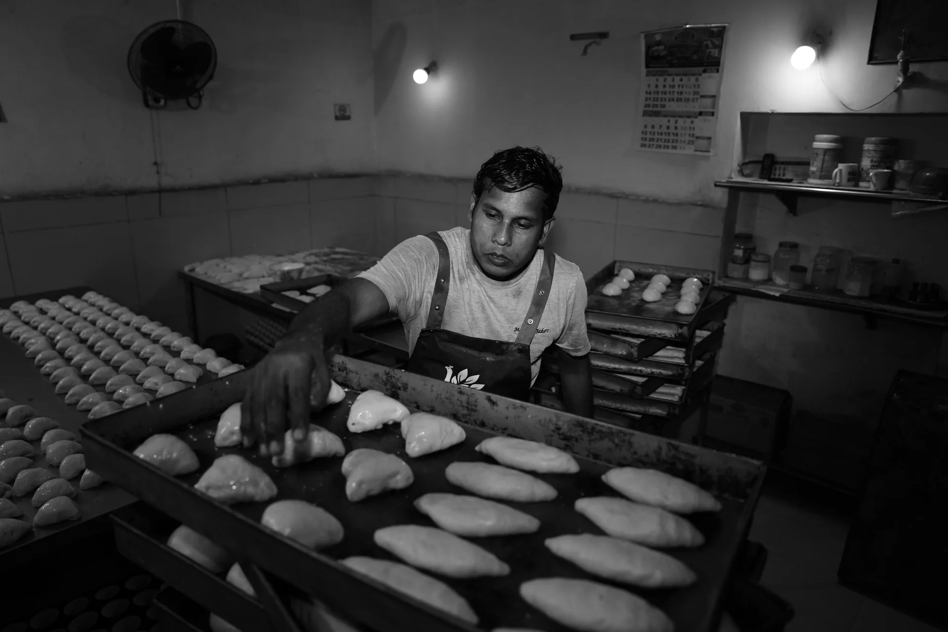 A baker arranging portions of dough on baking trays.