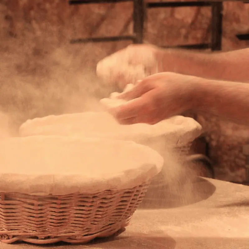 Flour scattered by hand over traditional woven bread baskets.