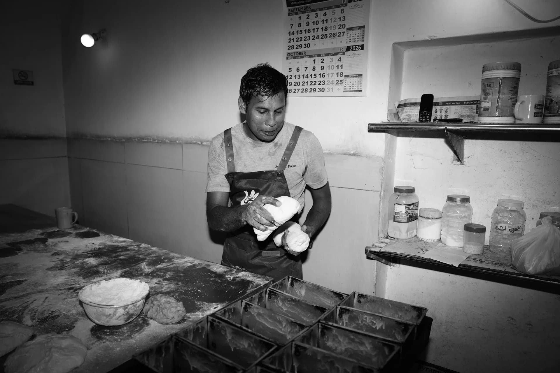 A baker shaping dough by hand at a floured workbench.