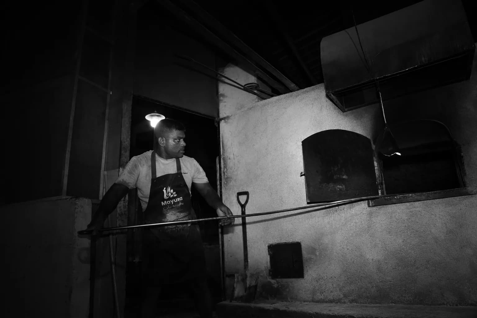 A baker tending loaves inside a traditional brick oven.